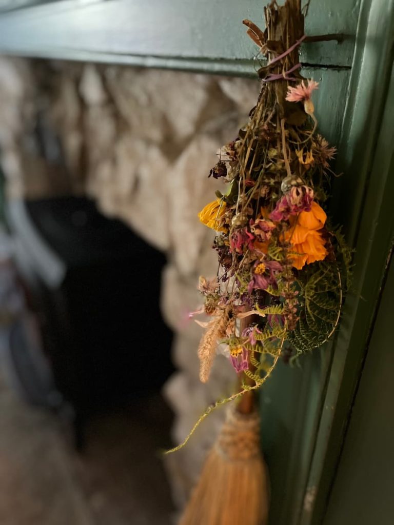 a bouquet of dried flowers hanging upside down on a fireplace mantel